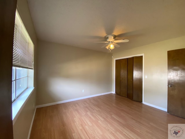 unfurnished bedroom featuring ceiling fan, a closet, and light wood-type flooring