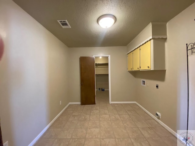 laundry room featuring hookup for an electric dryer, cabinets, a textured ceiling, and hookup for a washing machine