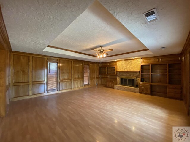 507 E Fannin St, Dekalb, TX 75559 - unfurnished living room with ceiling fan, hardwood / wood-style flooring, a raised ceiling, and a fireplace