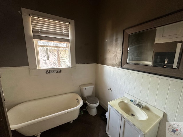 bathroom with vanity, toilet, tile walls, and a tub to relax in