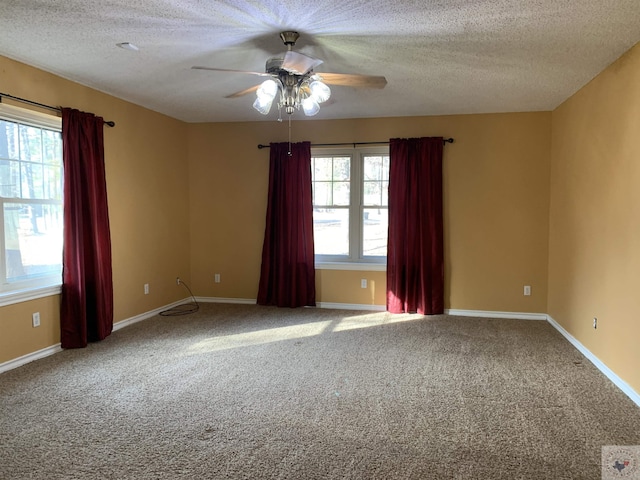 carpeted empty room featuring ceiling fan, a textured ceiling, and a healthy amount of sunlight