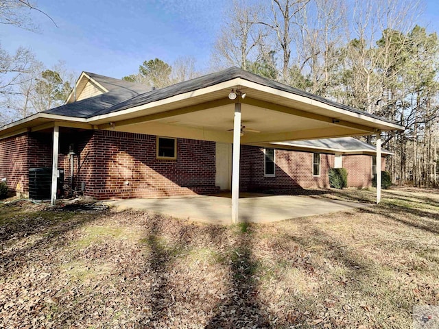 view of side of home with a carport, brick siding, and dirt driveway