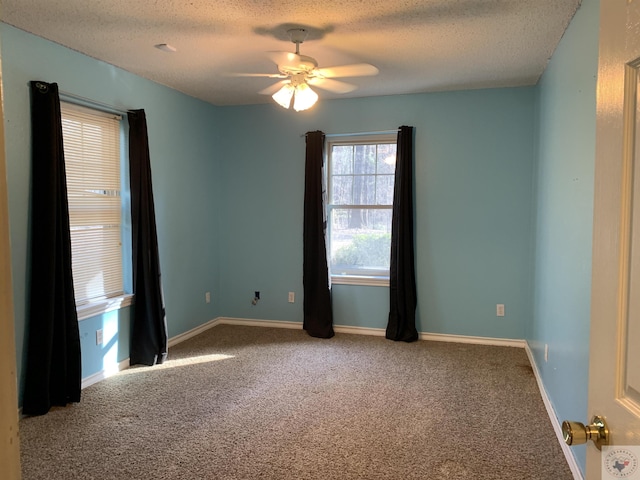 empty room with a textured ceiling, a ceiling fan, baseboards, and carpet floors