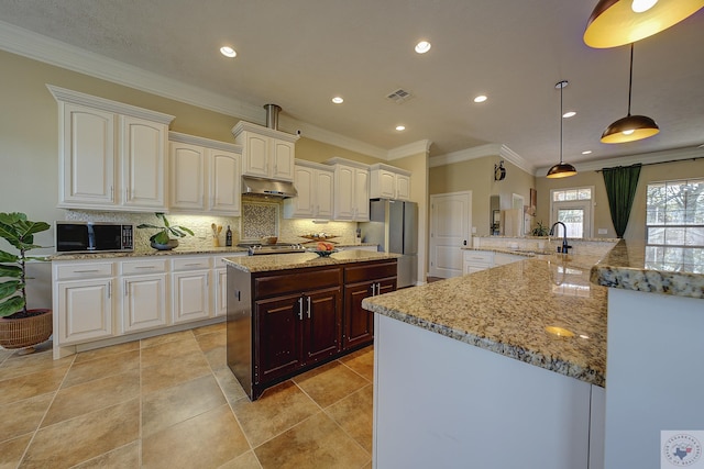 kitchen featuring pendant lighting, sink, tasteful backsplash, light stone counters, and stainless steel refrigerator