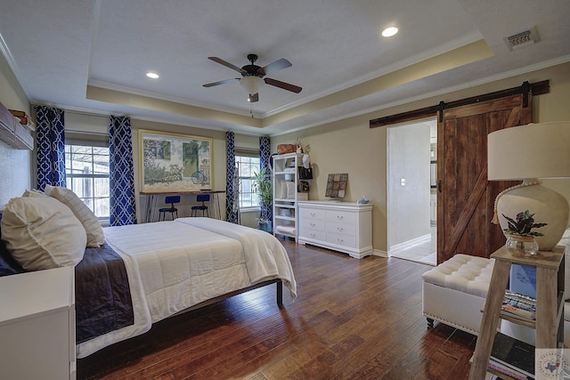 bedroom with ceiling fan, a tray ceiling, dark hardwood / wood-style floors, and a barn door