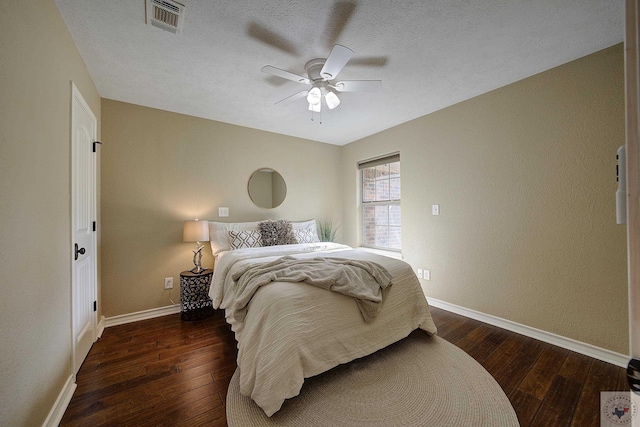 bedroom with a textured ceiling, ceiling fan, and dark hardwood / wood-style flooring