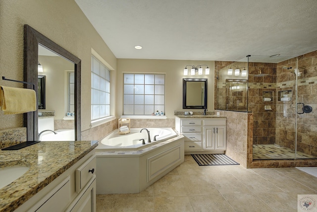 bathroom with a textured ceiling, tile patterned floors, vanity, and separate shower and tub