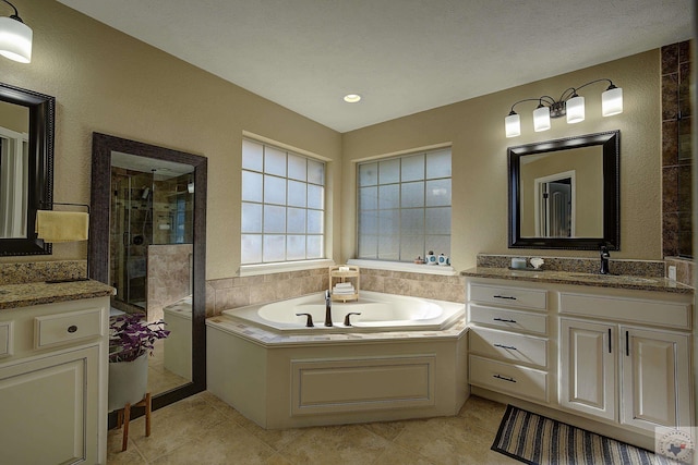 bathroom with a textured ceiling, tile patterned floors, vanity, and independent shower and bath