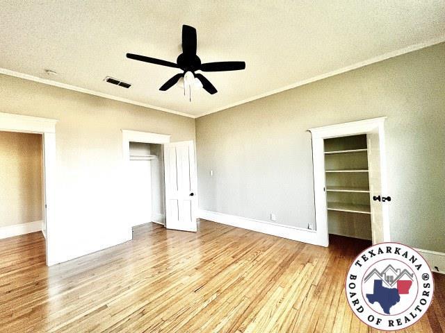 unfurnished room featuring visible vents, baseboards, ornamental molding, ceiling fan, and light wood finished floors