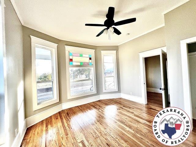 spare room with baseboards, wood finished floors, and a healthy amount of sunlight