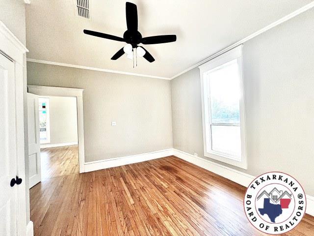 unfurnished room with a ceiling fan, wood finished floors, baseboards, and ornamental molding
