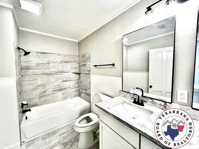 bathroom featuring ornamental molding, toilet, vanity, and  shower combination