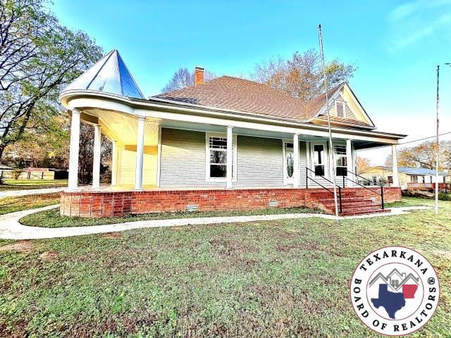 view of front of house featuring a porch, a chimney, and a front lawn