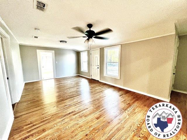 spare room featuring visible vents, baseboards, a ceiling fan, a textured ceiling, and wood finished floors