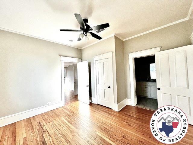 unfurnished bedroom featuring ornamental molding, baseboards, ceiling fan, and wood finished floors