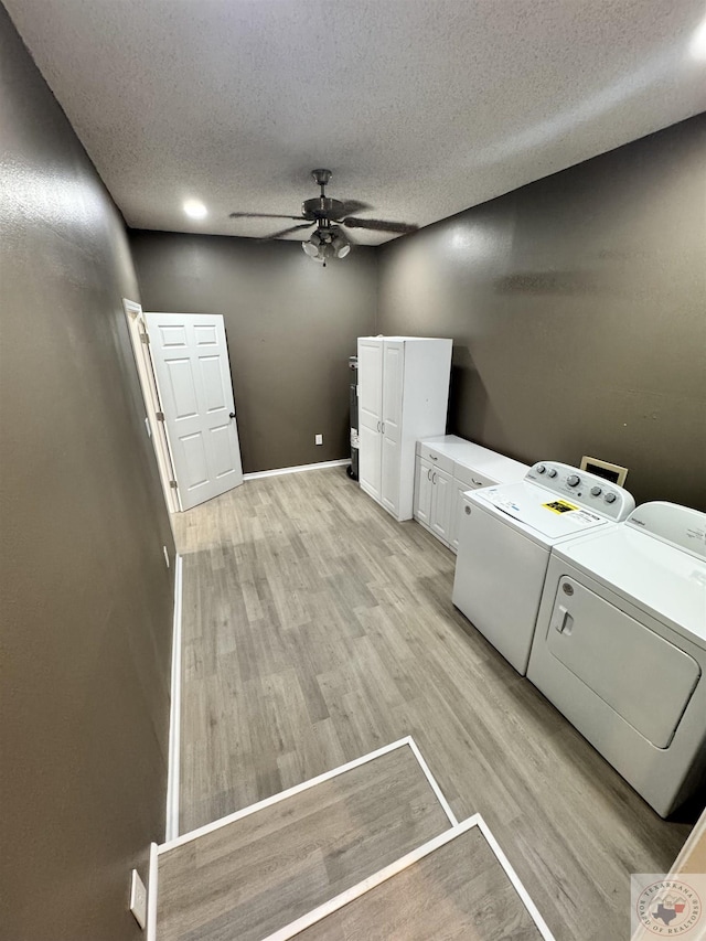 clothes washing area featuring light hardwood / wood-style floors, a textured ceiling, separate washer and dryer, ceiling fan, and cabinets