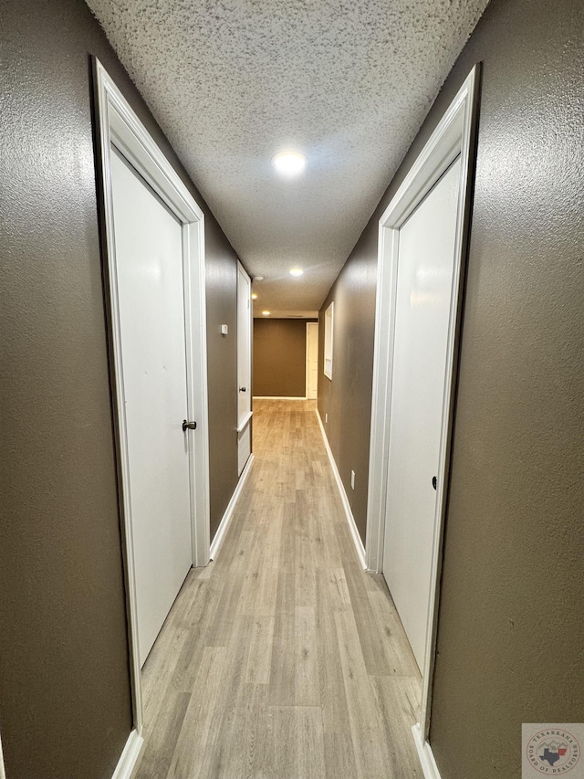 corridor featuring light hardwood / wood-style floors and a textured ceiling