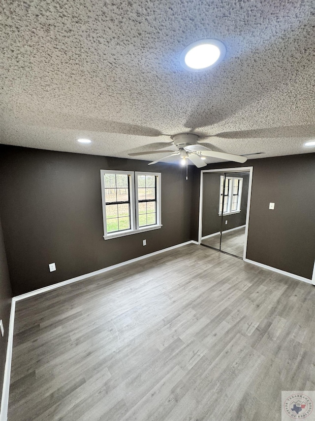 unfurnished bedroom with a closet, ceiling fan, light hardwood / wood-style floors, and a textured ceiling