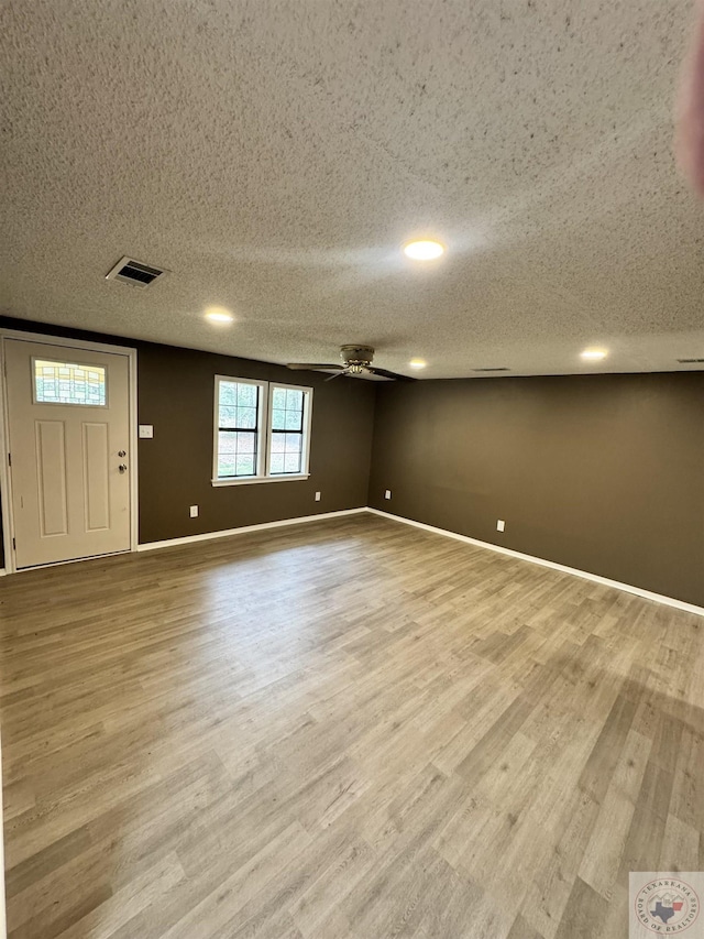 interior space featuring ceiling fan, a textured ceiling, and light wood-type flooring