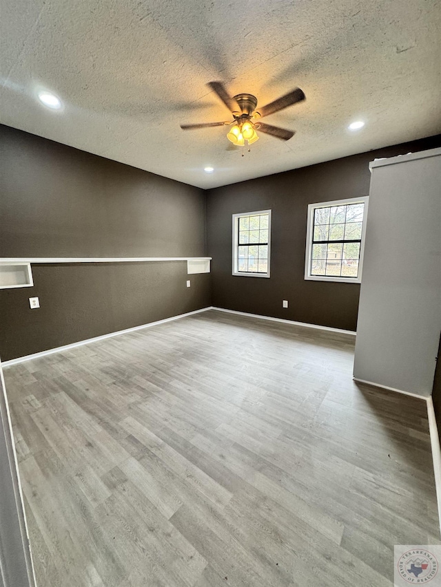 unfurnished room featuring ceiling fan, a textured ceiling, and light wood-type flooring