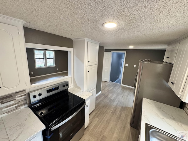 kitchen with light wood-type flooring, white cabinetry, a textured ceiling, decorative backsplash, and stainless steel appliances