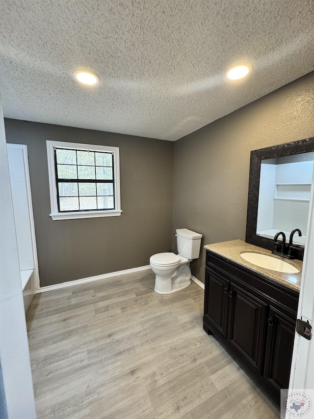 bathroom with a textured ceiling, toilet, vanity, and hardwood / wood-style floors