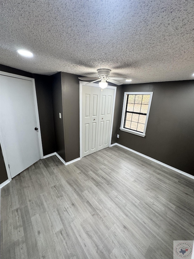 unfurnished bedroom featuring ceiling fan, light hardwood / wood-style floors, and a textured ceiling