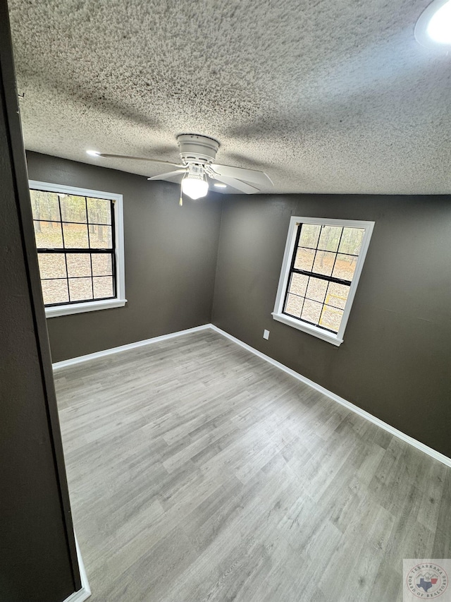 empty room featuring ceiling fan, light hardwood / wood-style floors, and a textured ceiling