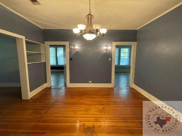 unfurnished dining area with built in features, a chandelier, crown molding, and hardwood / wood-style floors