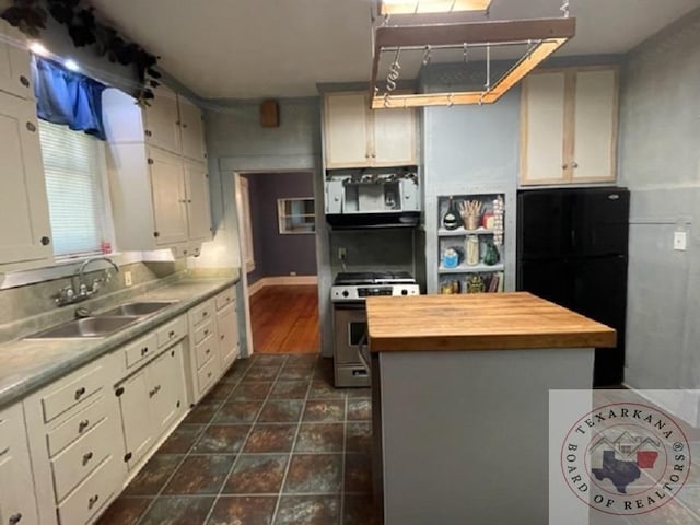 kitchen with gas range, sink, white cabinets, and a center island