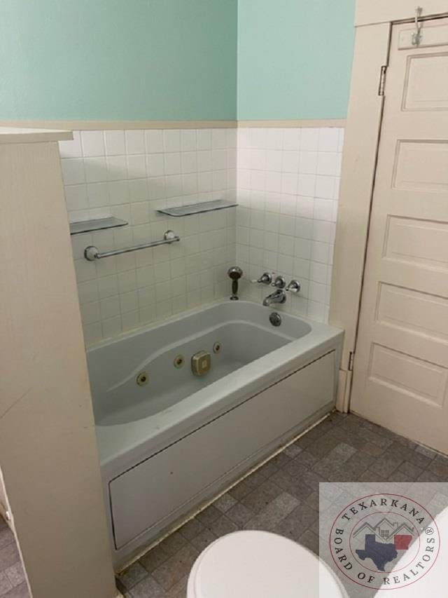 bathroom featuring a tub, tile walls, and toilet