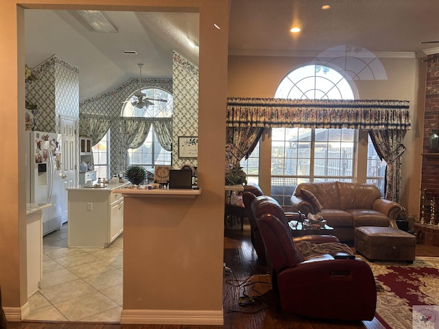 living room with vaulted ceiling, light tile patterned floors, ceiling fan, and ornamental molding