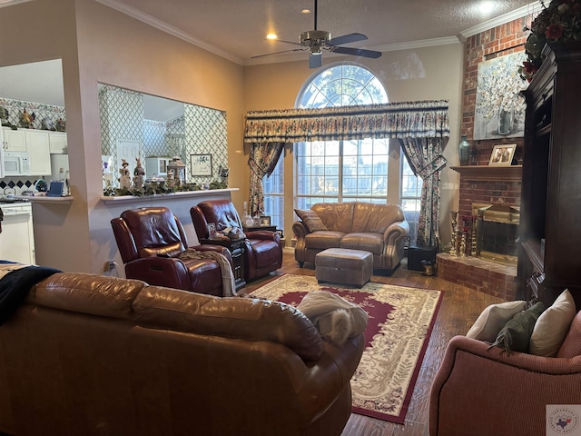 living room featuring wood-type flooring, a fireplace, ceiling fan, and ornamental molding