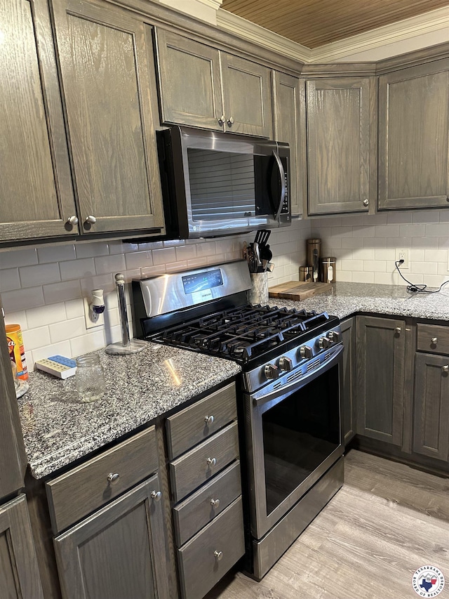 1002 Champion St, Texarkana, TX 75503 - kitchen featuring appliances with stainless steel finishes, tasteful backsplash, light wood-style flooring, stone counters, and crown molding