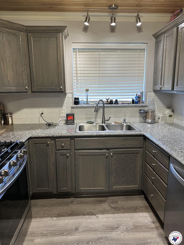 1002 Champion St, Texarkana, TX 75503 - kitchen with appliances with stainless steel finishes, crown molding, light wood finished floors, a sink, and tasteful backsplash