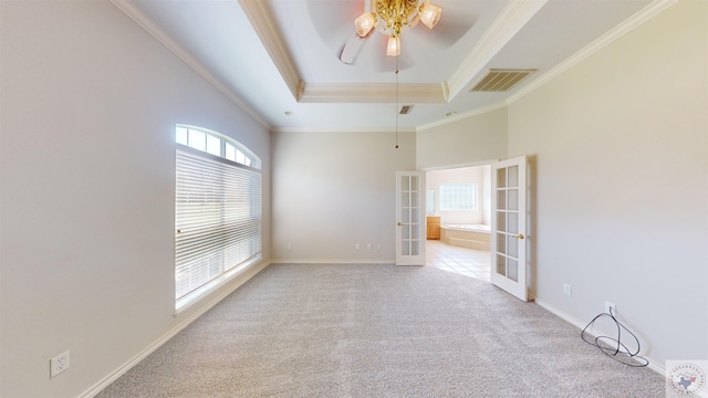 carpeted empty room with ceiling fan, a tray ceiling, crown molding, and french doors