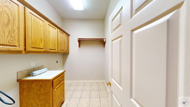 washroom with hookup for an electric dryer, light tile patterned floors, and cabinets