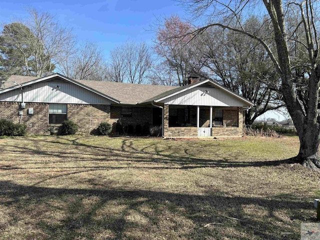 view of front of house featuring roof with shingles, a chimney, a front lawn, and brick siding