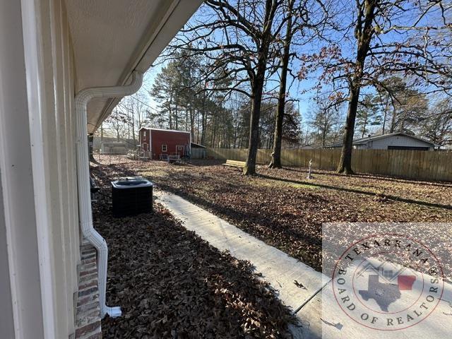 33 Timberlane St, Texarkana, TX 75501 - view of yard featuring central AC unit, fence, and an outbuilding