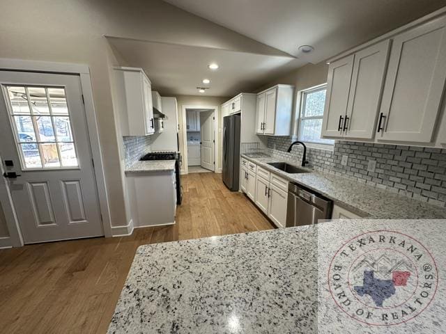 33 Timberlane St, Texarkana, TX 75501 - kitchen with a sink, freestanding refrigerator, stainless steel dishwasher, light wood-style floors, and light stone counters
