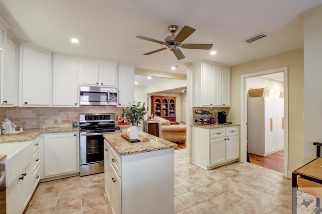 kitchen with appliances with stainless steel finishes, white cabinets, light stone counters, and decorative backsplash