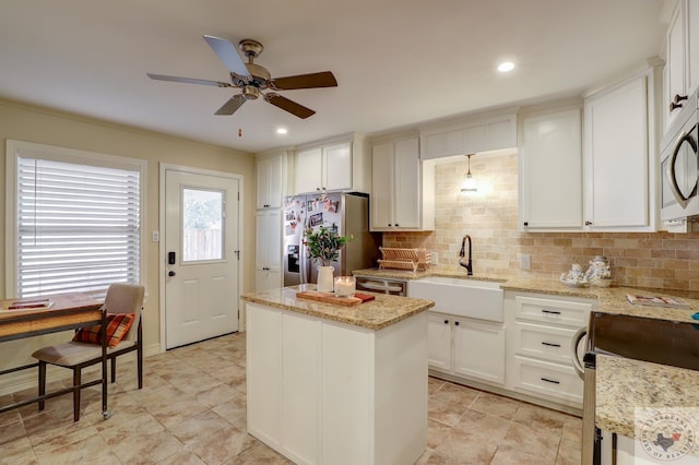 kitchen with sink, light stone counters, white cabinetry, a kitchen island, and stainless steel appliances