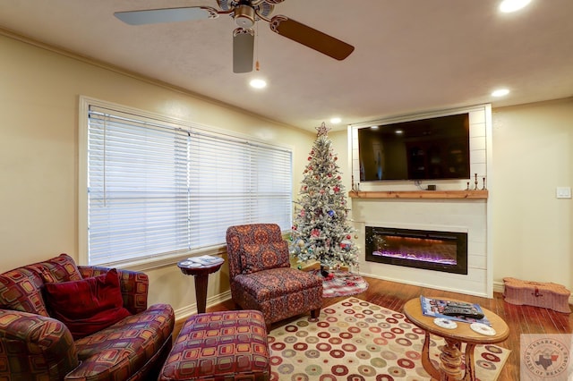 living room with wood-type flooring, a large fireplace, and crown molding