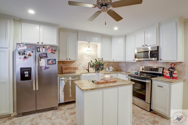 kitchen with light stone counters, tasteful backsplash, a kitchen island, stainless steel appliances, and white cabinets