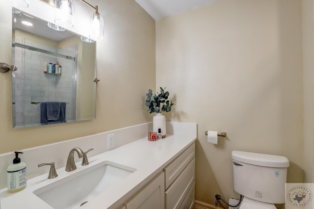 bathroom featuring a shower with door, vanity, and toilet