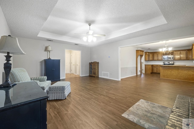 living room featuring ceiling fan with notable chandelier, a raised ceiling, dark hardwood / wood-style floors, and a textured ceiling