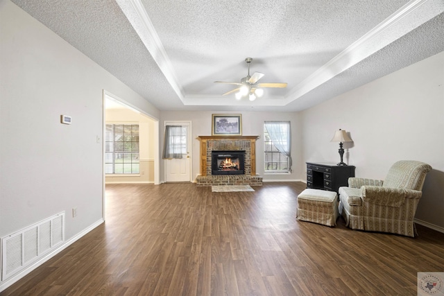 living room with dark wood-type flooring, plenty of natural light, and a raised ceiling