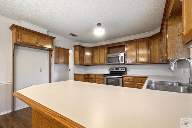 kitchen featuring kitchen peninsula, dark hardwood / wood-style flooring, sink, a textured ceiling, and stainless steel appliances