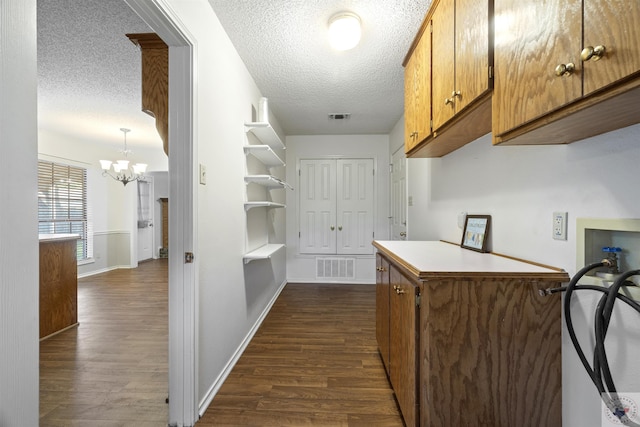 kitchen featuring a textured ceiling, a chandelier, hanging light fixtures, and dark hardwood / wood-style flooring