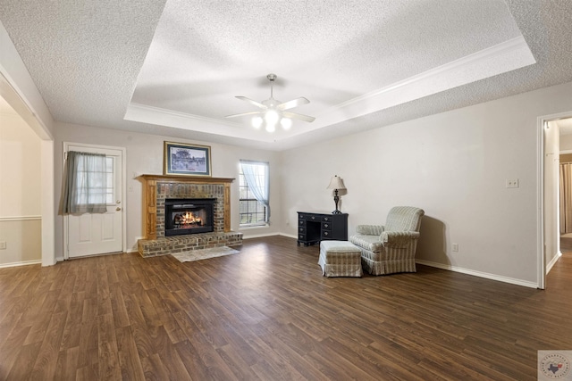 unfurnished room featuring a fireplace, a textured ceiling, dark hardwood / wood-style floors, and a raised ceiling